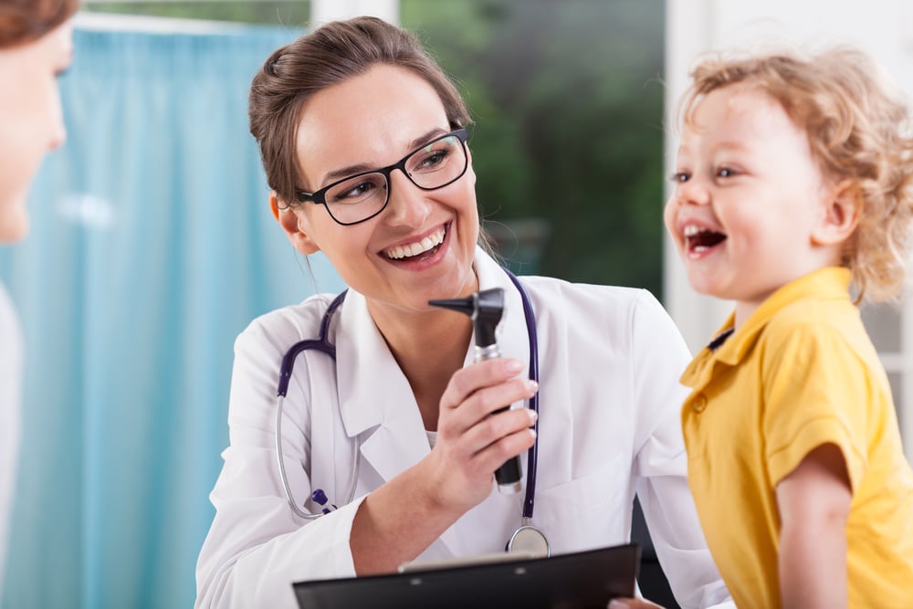 Glücklicher kleiner Junge wird durch eine Krankenpflegerin untersucht